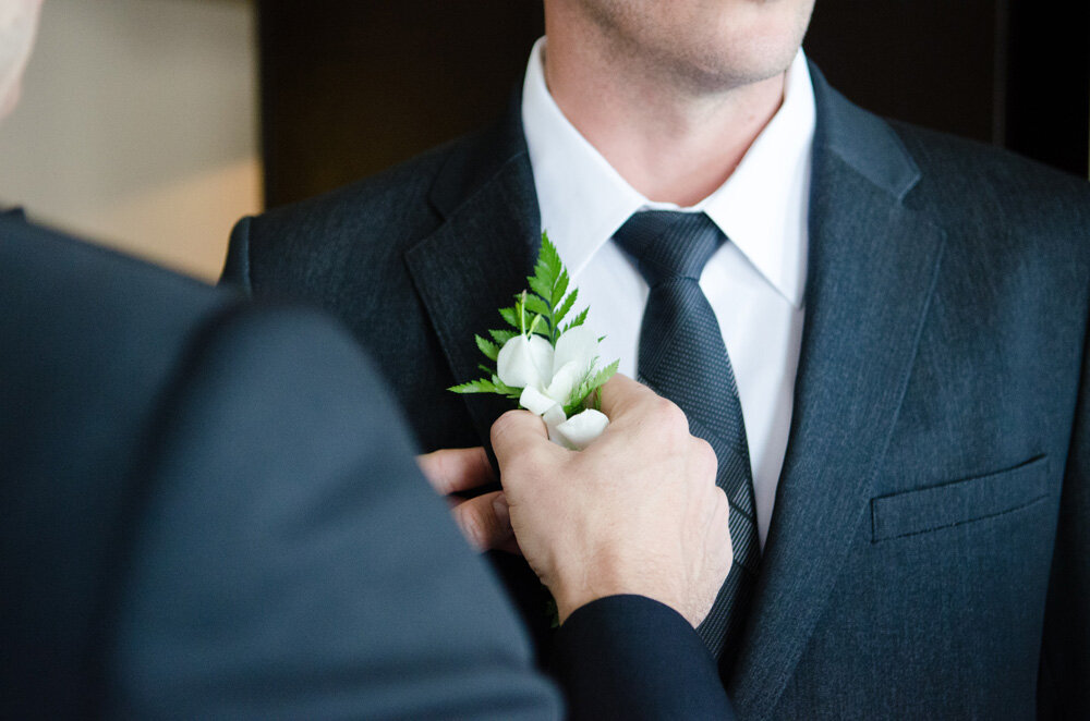 groomsman helping the groom with lapel