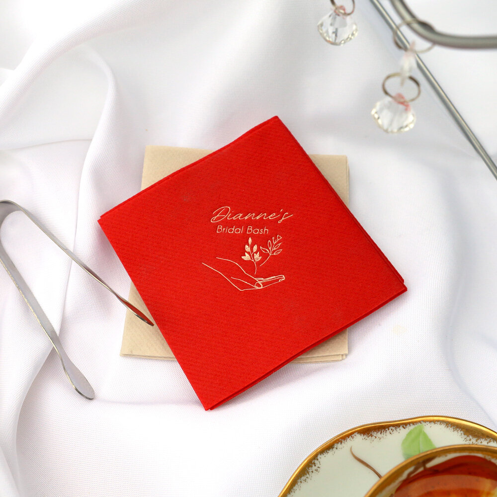 Close up of red napkin that says Dianne’s Bridal Bash with a floral tea favor sitting on top of it.