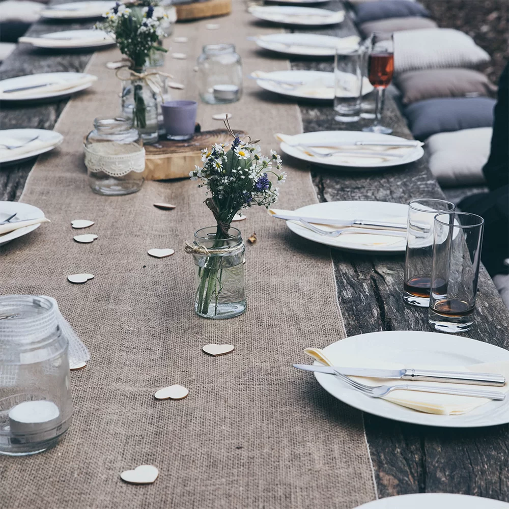 [glasses plates arranged around an outdoor wooden table], credit Stella de Smit