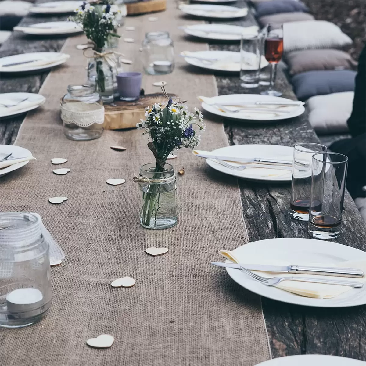[glasses plates arranged around an outdoor wooden table], credit Stella de Smit