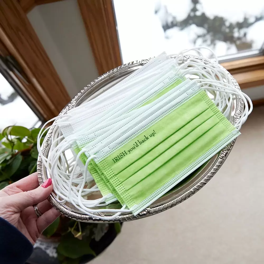 a hand holding a tray of green face masks