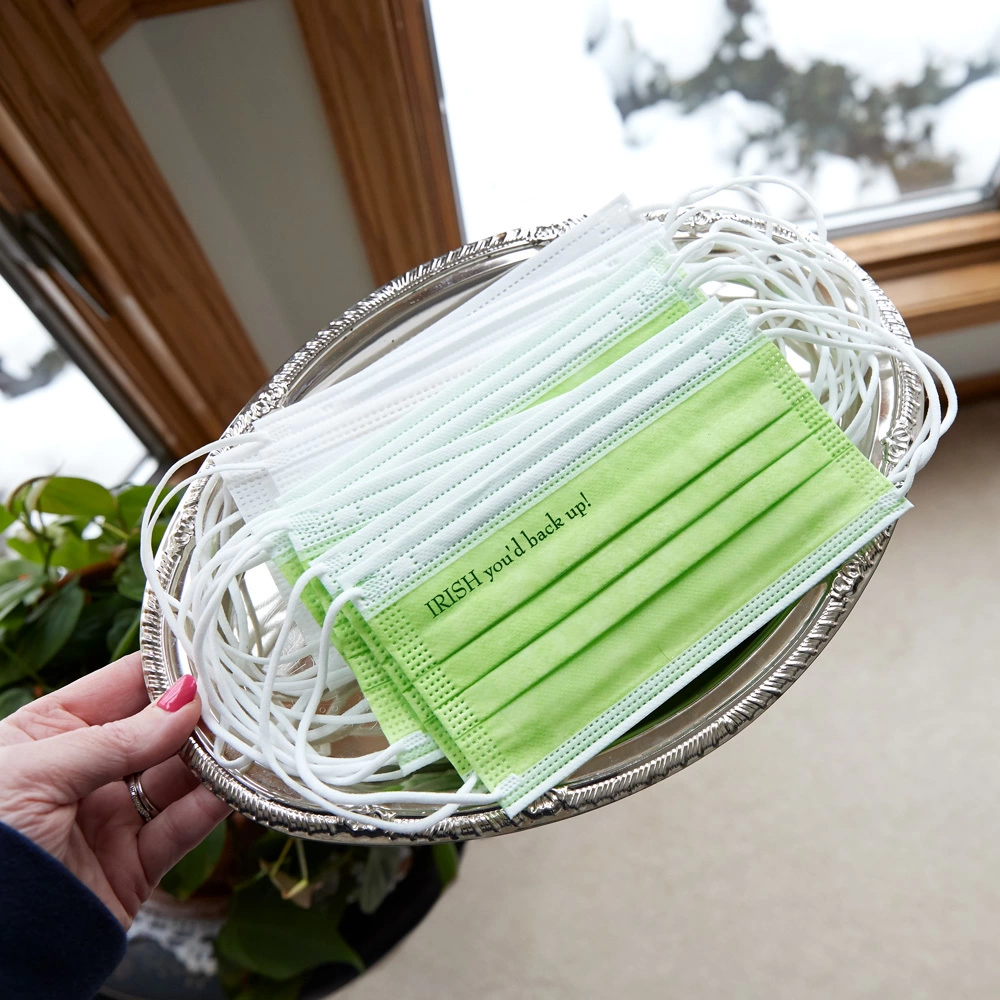 a hand holding a tray of green face masks