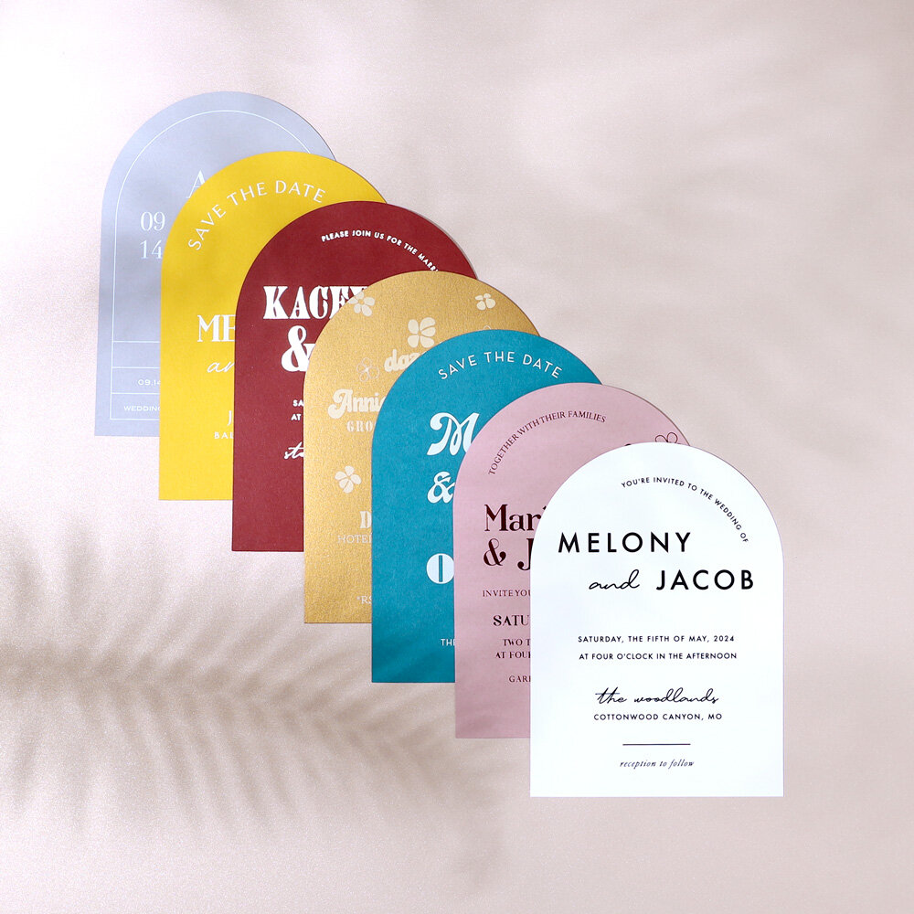 stack of seven arch invitations on a taupe floral background