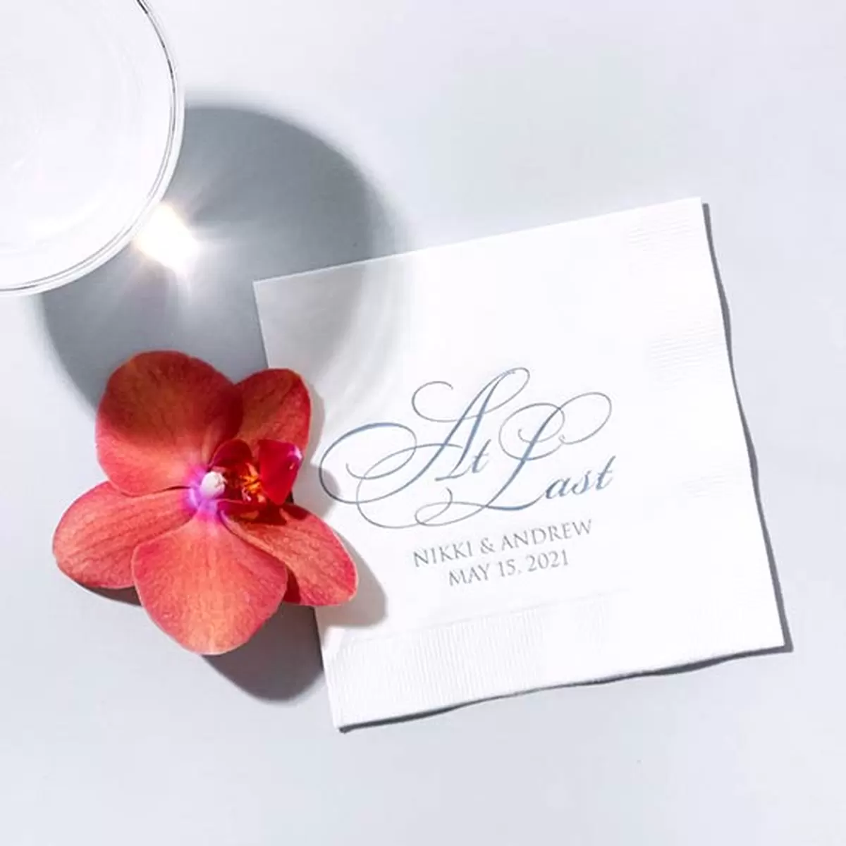 White cocktail napkin with At Last design with names stamped in stain French blue foil