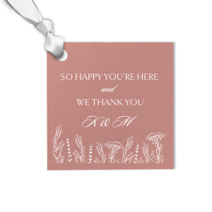 Enhance your gift presentation with our stunning personalized gift tag, crafted with the luxurious touch of foil printing. This elegant square tag conveys your gratitude with the message "So Happy You're Here and We Thank You,". The shimmering foil print beautifully highlights the wildflower floral motif at the base, adding a touch of glamour and elegance.