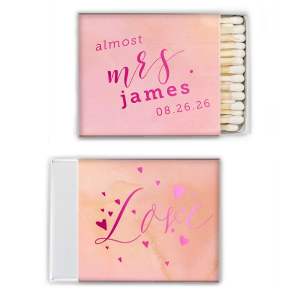 The Excitement Ignites! Celebrate the bride-to-be with the Almost Mrs. Matchbox. Featuring a dramatic "almost Mrs." script on the front and "Love" surrounded by floating hearts on the back, this vibrant design captures the rising excitement as the big day approaches. Perfect for wedding showers and bachelorette parties!