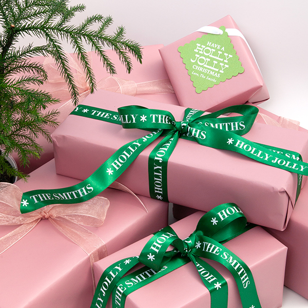 green holly jolly ribbon on a pink background