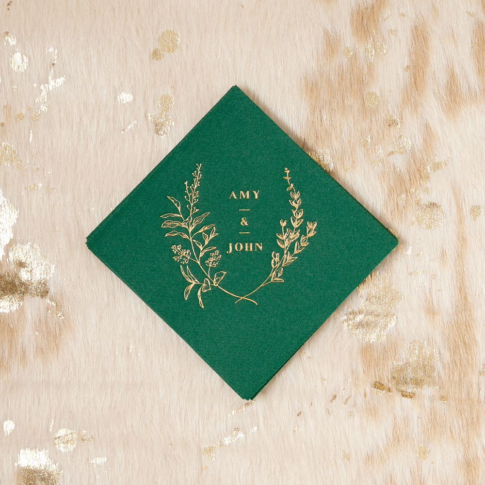 Green napkin printed in gold with floral crest and couple's names
