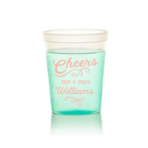 The Swirling Cheers Cup exudes exuberance. The design features "Cheers" fancifully scripted, underscored by a flourish. Below, the couple's titles "Mr. and Mrs." lead into their last name, further accentuated by an ornate flourish. These swirling designs add a sense of fanciful charm, making the cup a perfect vessel for toasting. 