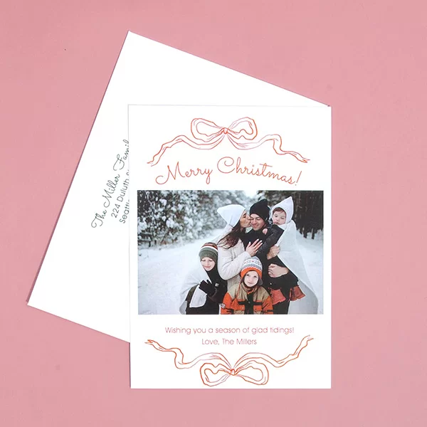 Printed holiday photo card on a pink background