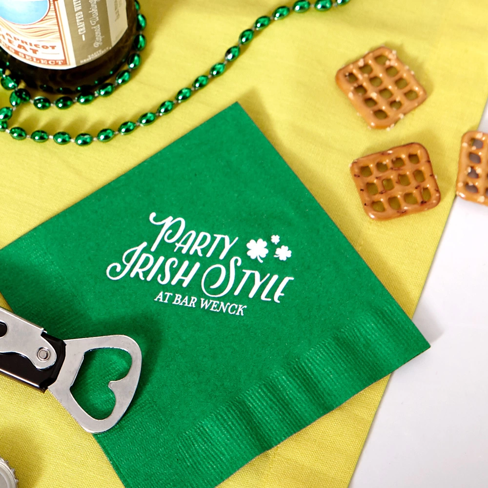 green “party Irish style” napkin on a table next to a bottle opener