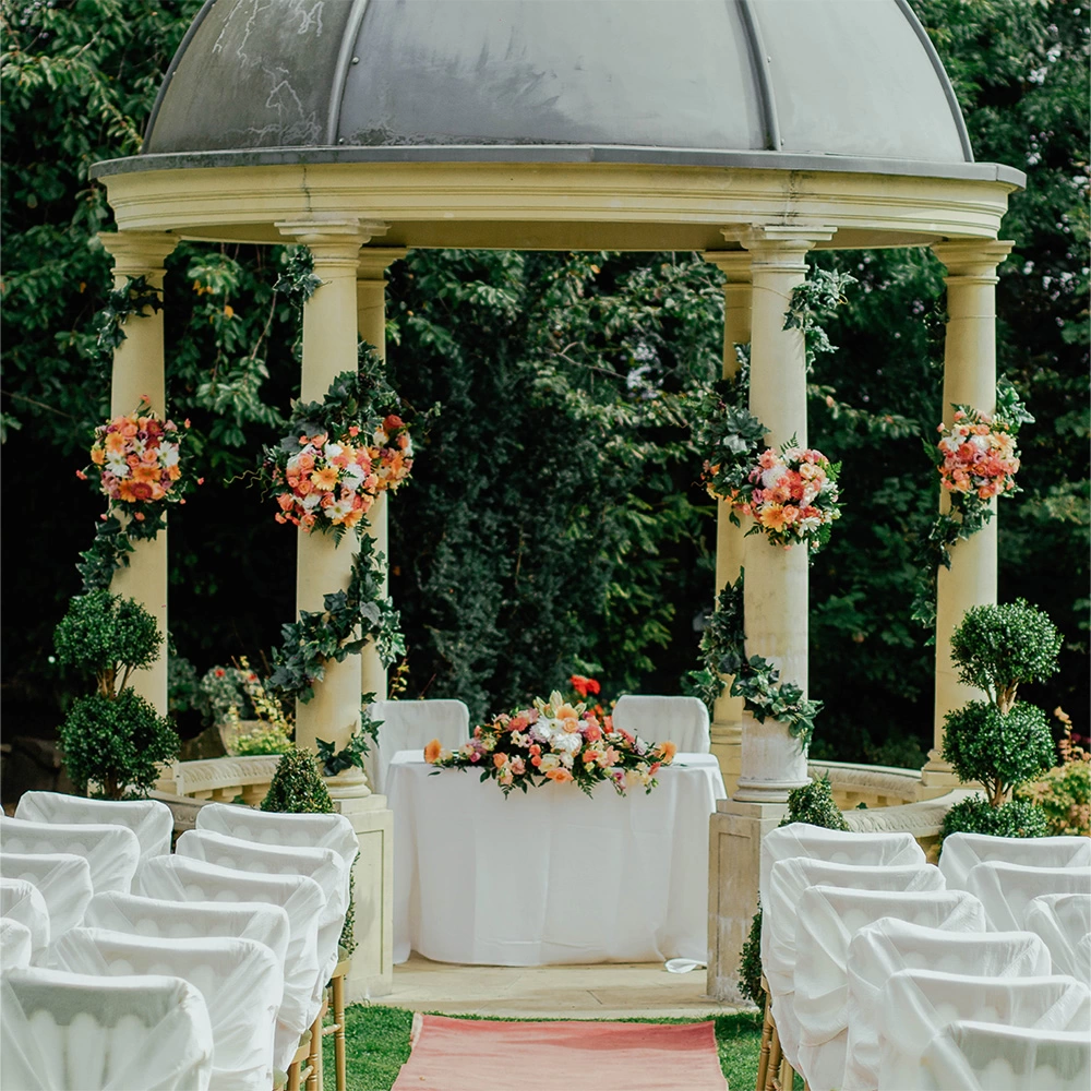 view looking down an aisle towards a table and chairs inside of a gazebo], credit Jeremy Wong Weddings.