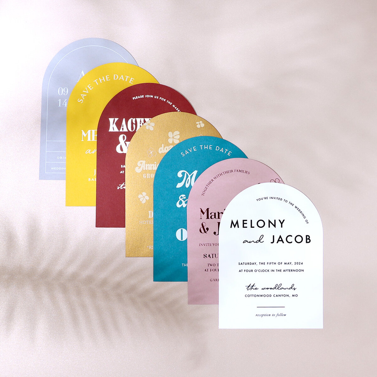 stack of seven arch invitations on a taupe floral background