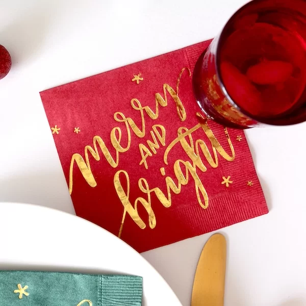 Merry and Bright napkins on table with glass