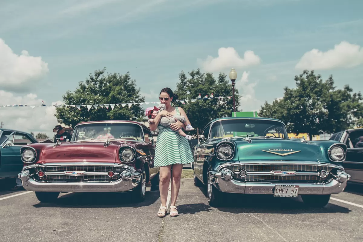 retro photo of mother and baby near classic cars