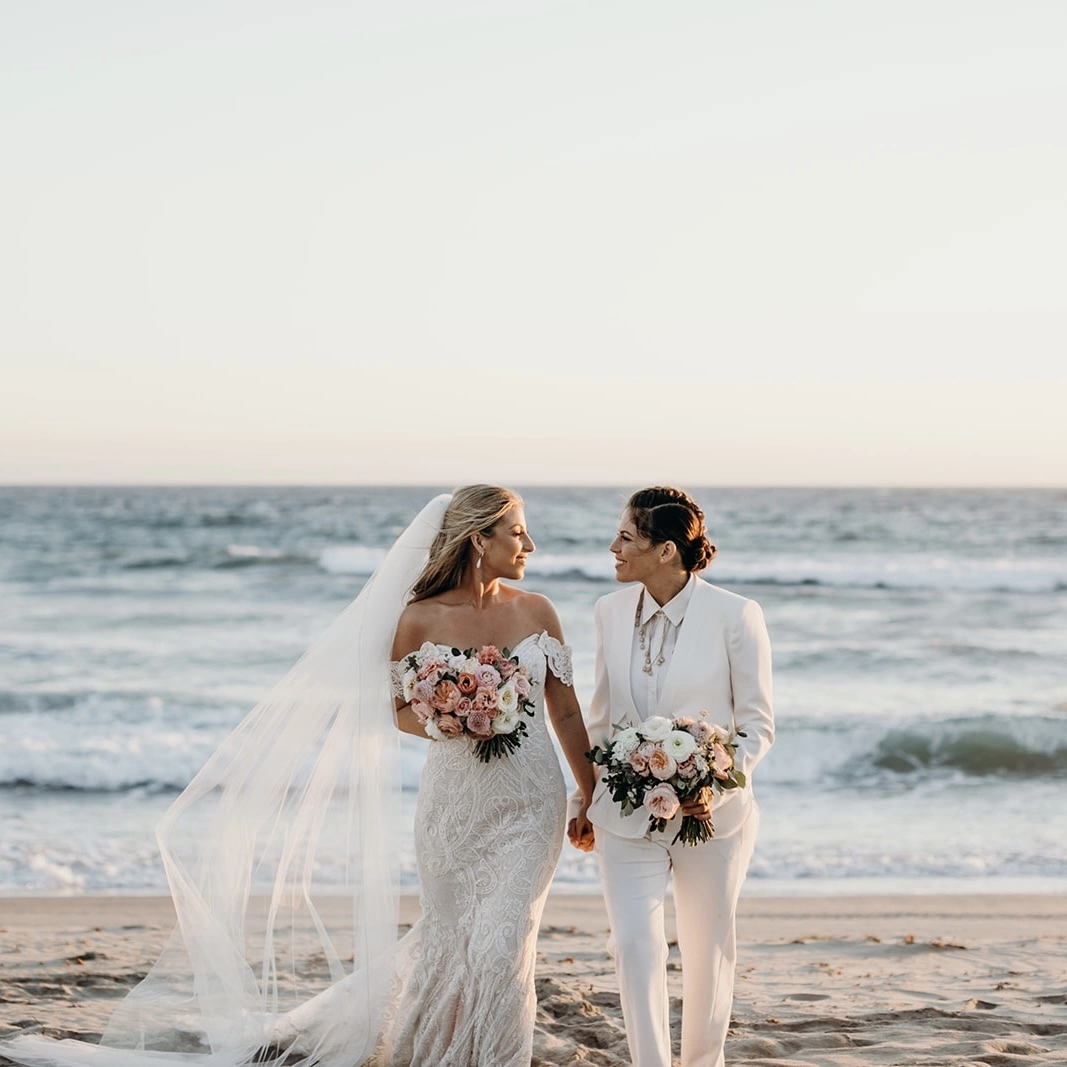Happy newlyweds walking on the beach, hand in hand 