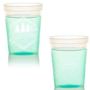Set off on a new journey with the Adventure Begins Cup, a two-sided celebration of nature and new beginnings. One side, framed by a hexagonal border, showcases ‘the adventure begins’ on a banner, flanked by diverse evergreen trees and the couple’s initials. The other side commemorates the event with the location and date, perfectly encapsulating the spirit of adventure and personal milestones."