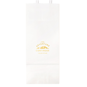The Adventure Continues Bag encapsulates the spirit of exploration and shared journey. Featuring a graphic of snow-capped mountains with "The Adventure" arching over and "CONTINUES" below, it symbolizes the ongoing journey of the couple. Their names personalize this narrative of continuous adventure and discovery as they embark on life together. 
