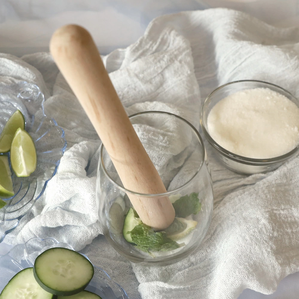 Rolling pin being used to muddle lime, mint, and sugar
