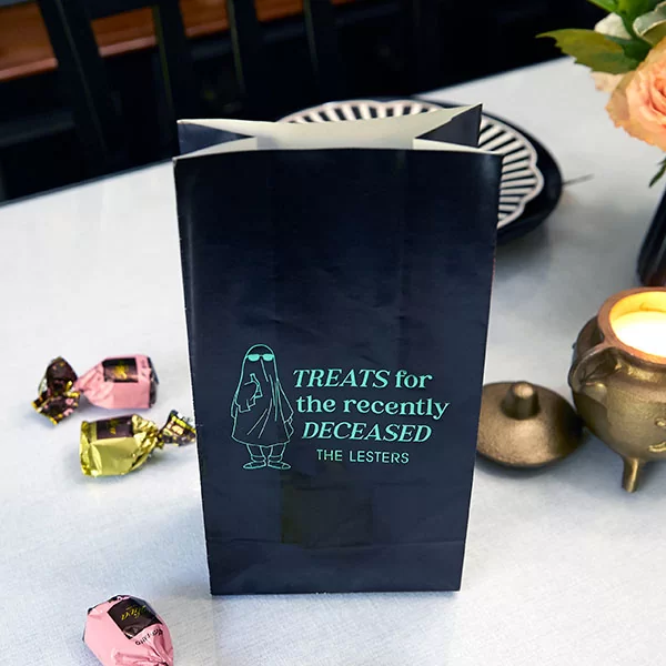 Treats For The Recently Deceased Bag aside lit candle and treats