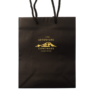 The Adventure Continues Bag encapsulates the spirit of exploration and shared journey. Featuring a graphic of snow-capped mountains with "The Adventure" arching over and "CONTINUES" below, it symbolizes the ongoing journey of the couple. Their names personalize this narrative of continuous adventure and discovery as they embark on life together. 
