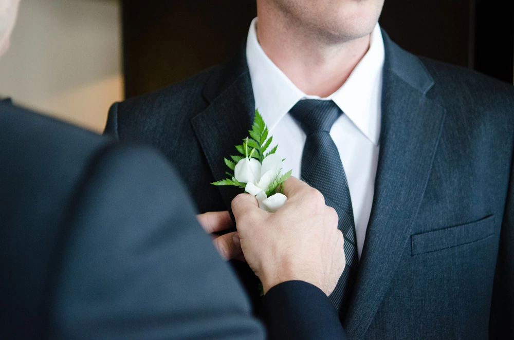 groomsman helping the groom with lapel