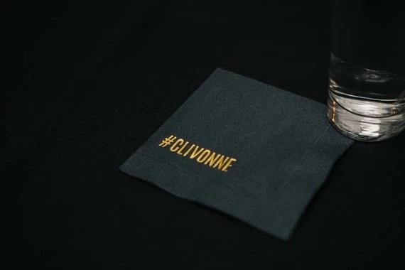 A black cocktail napkin with the couple's hashtag