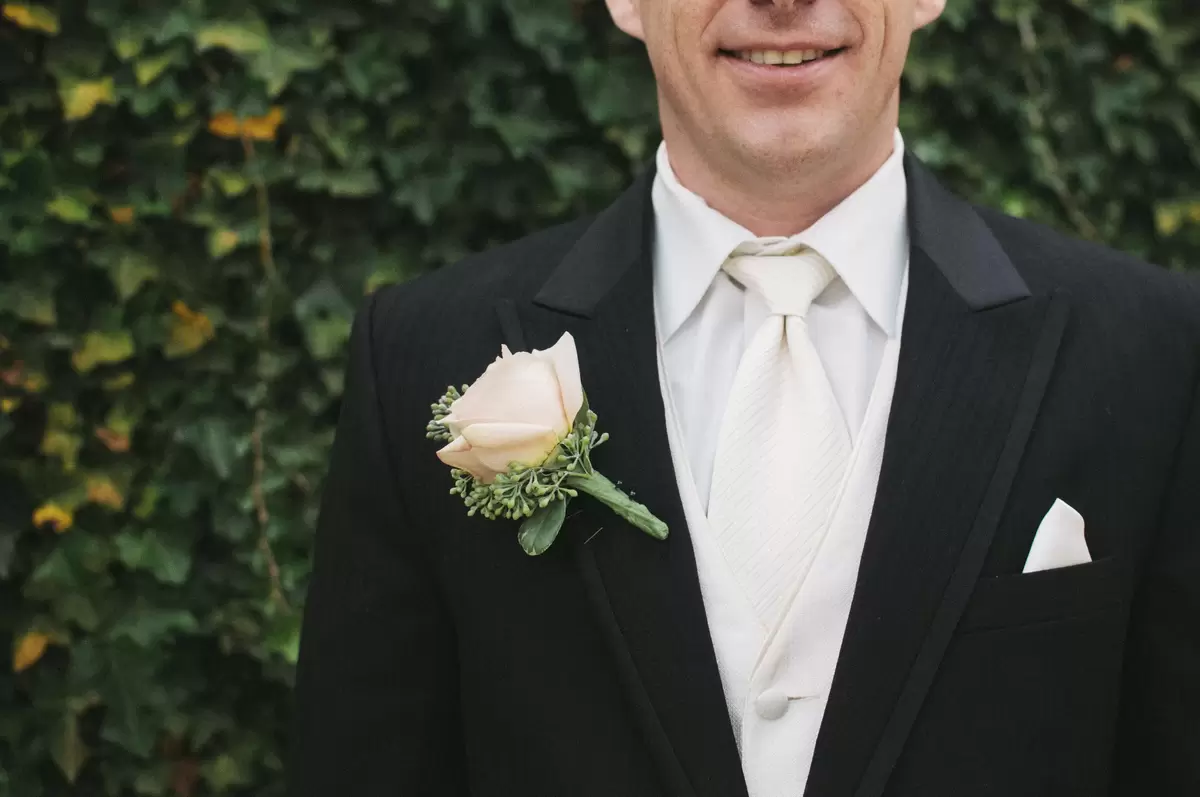 man wearing white tie in front of ivy covered wall
