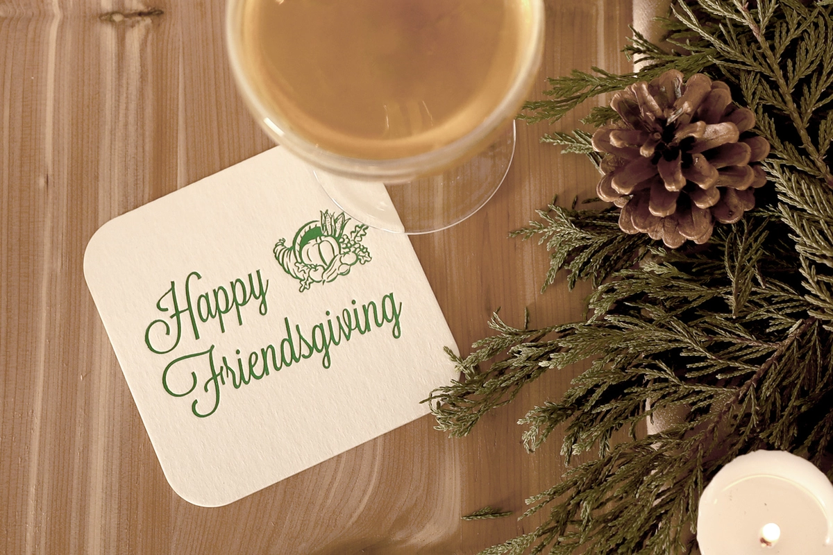 Coaster under a wine glass that says "Happy Friendsgiving" with a graphic of a turkey 